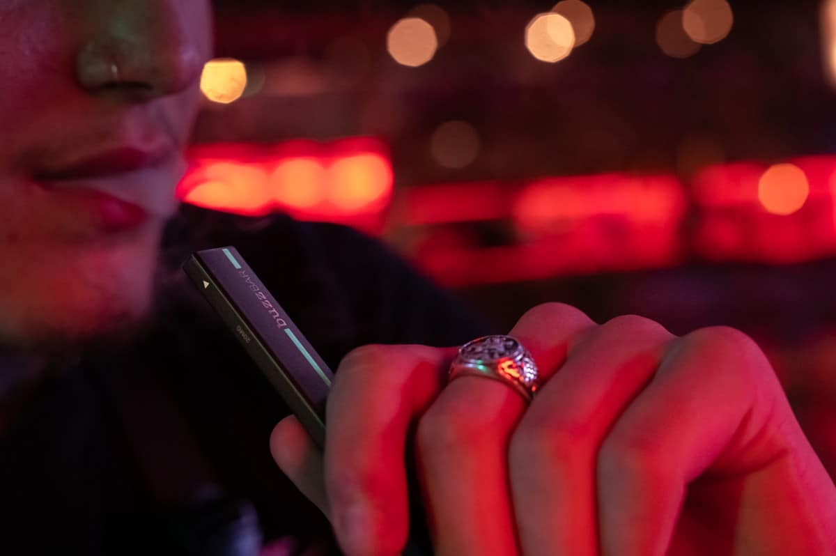 Man taking a drag from a Buzz Bar Menthol Disposable Vape at night